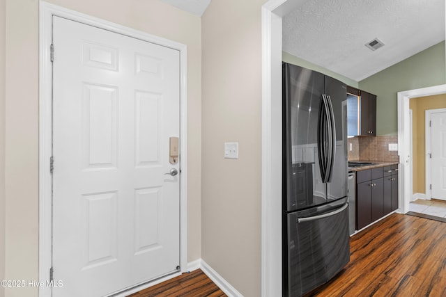 kitchen with baseboards, decorative backsplash, freestanding refrigerator, dark wood-style floors, and visible vents