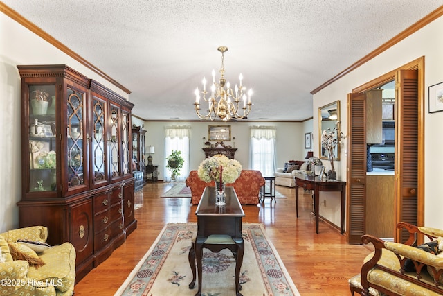 dining area featuring a chandelier, wood finished floors, a textured ceiling, and crown molding