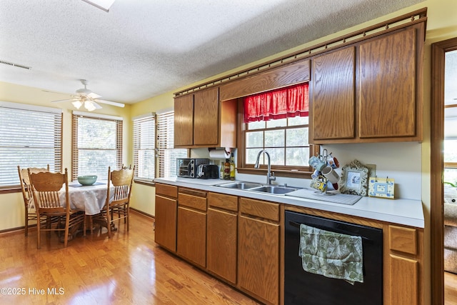 kitchen with a sink, a textured ceiling, light wood-type flooring, ceiling fan, and light countertops