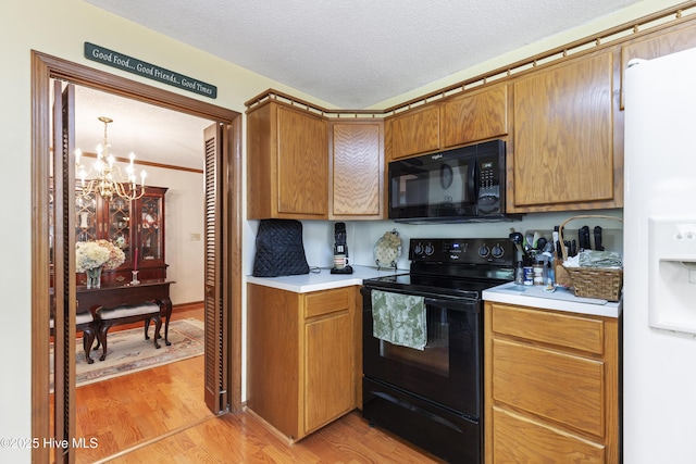 kitchen featuring a textured ceiling, an inviting chandelier, light wood-style floors, light countertops, and black appliances