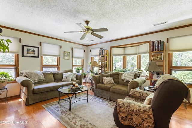 living room with ceiling fan, a wealth of natural light, visible vents, and light wood finished floors