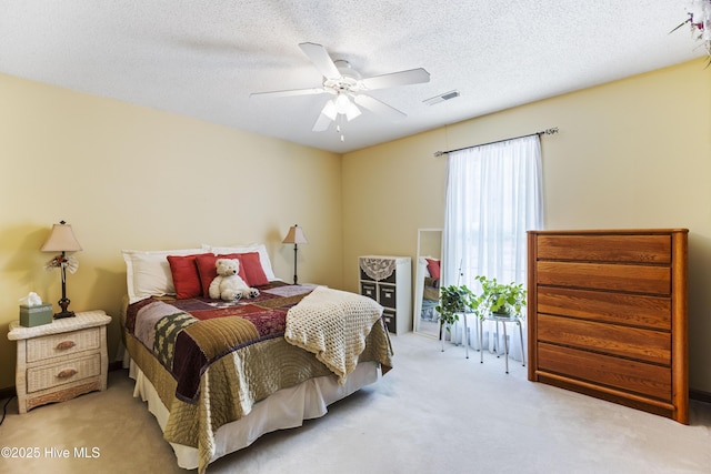 bedroom with a ceiling fan, visible vents, a textured ceiling, and carpet flooring