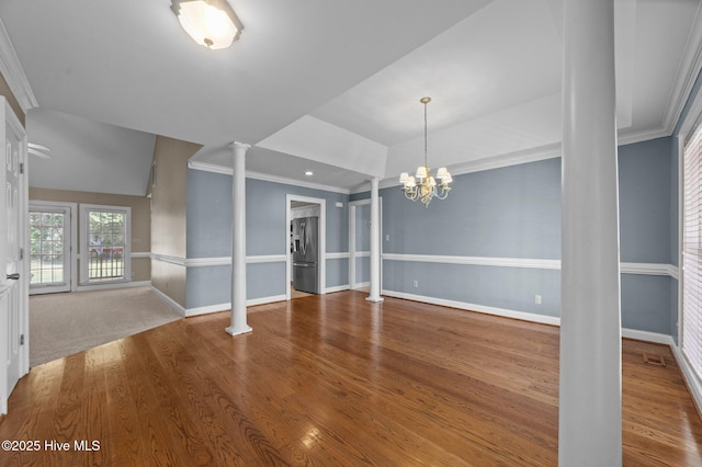 unfurnished dining area with ornamental molding, decorative columns, wood finished floors, baseboards, and a chandelier