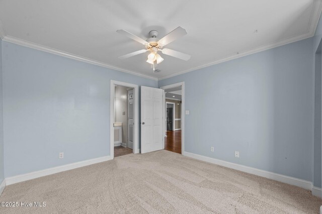 unfurnished bedroom featuring connected bathroom, carpet, a ceiling fan, baseboards, and ornamental molding