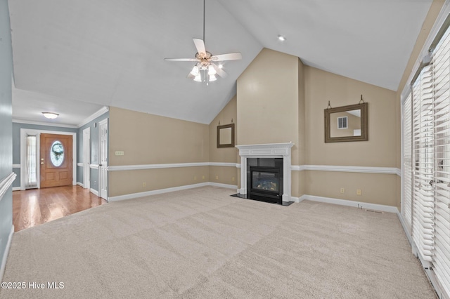 unfurnished living room with ceiling fan, carpet floors, baseboards, a fireplace with flush hearth, and vaulted ceiling