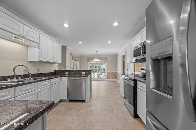 kitchen with white cabinets, crown molding, appliances with stainless steel finishes, a sink, and a chandelier