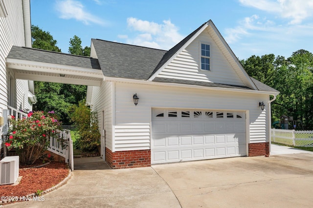view of home's exterior featuring a garage, fence, a shingled roof, and driveway