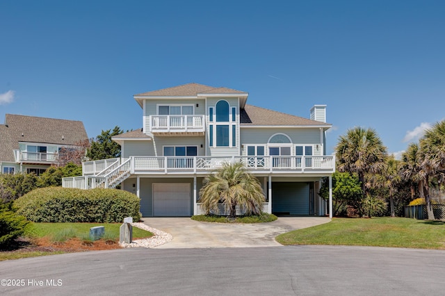 coastal home featuring a front lawn, a balcony, a carport, a chimney, and concrete driveway