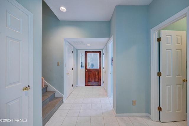 corridor with baseboards, visible vents, light tile patterned floors, and stairway