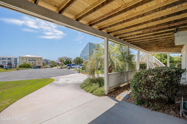 view of patio / terrace featuring stairway, concrete driveway, and a residential view