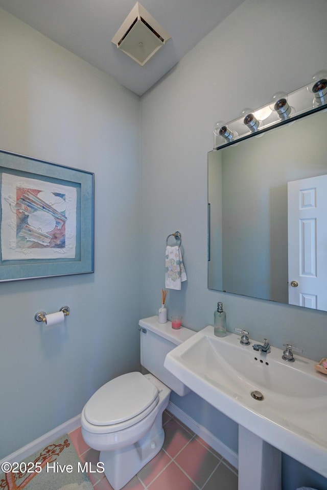 bathroom featuring tile patterned floors, toilet, baseboards, and a sink