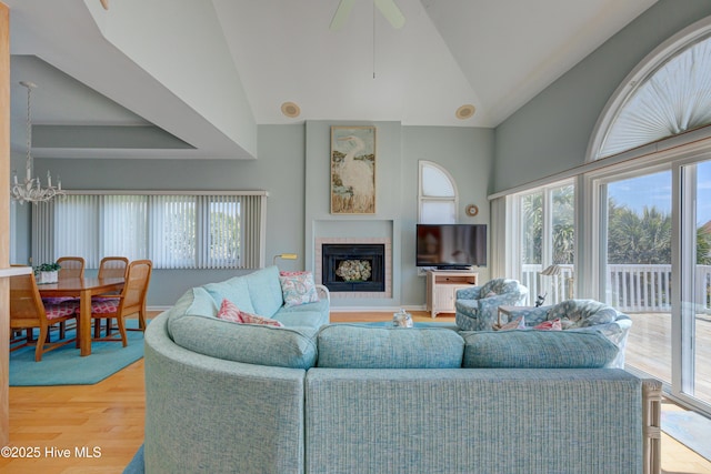 living room featuring a fireplace, a healthy amount of sunlight, lofted ceiling, and light wood-style floors