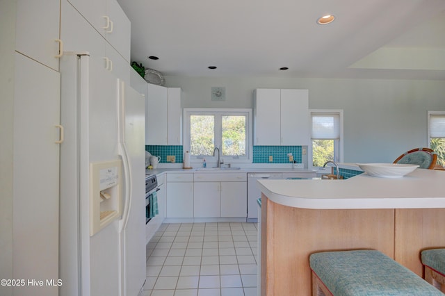 kitchen with light tile patterned floors, a sink, light countertops, dishwasher, and backsplash