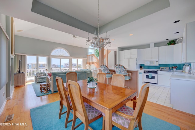 dining area featuring visible vents, a notable chandelier, and light wood finished floors