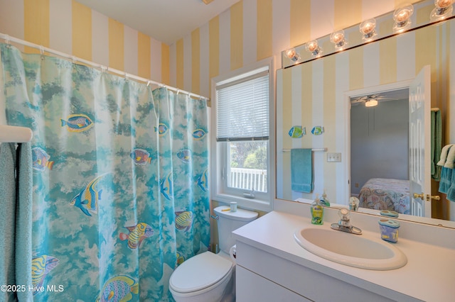 bathroom with vanity, toilet, a ceiling fan, wallpapered walls, and ensuite bathroom
