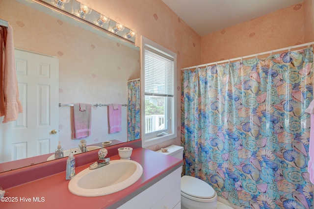full bath featuring a shower with shower curtain, toilet, and vanity