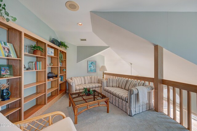 living area with visible vents, lofted ceiling, and carpet