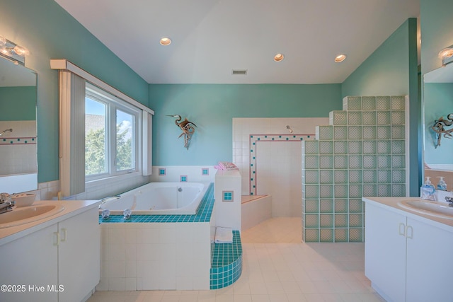 bathroom featuring two vanities, a bath, and a sink