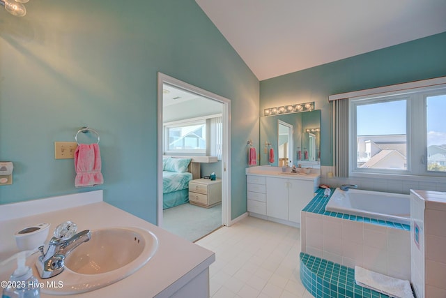 bathroom with vaulted ceiling, two vanities, a bath, and a sink