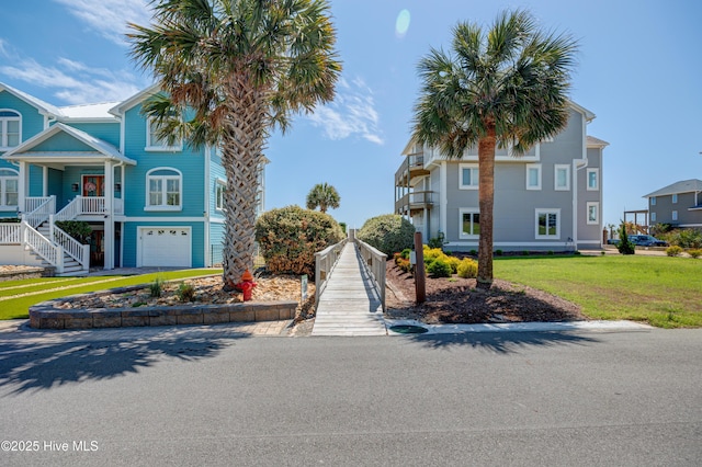 view of front of home with driveway, stairway, a front lawn, and a garage