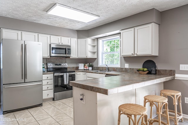 4915 Beulah Hill Church Rd, West End, NC 27376 - kitchen featuring stainless steel appliances, a sink, a peninsula, a textured ceiling, and white cabinetry