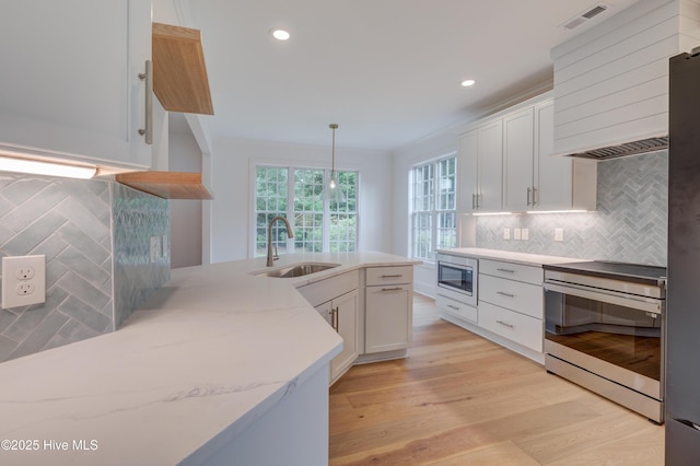 226 Bayfield Dr, Wilmington, NC 28411 - kitchen with appliances with stainless steel finishes, white cabinets, decorative backsplash, wall chimney range hood, and pendant lighting