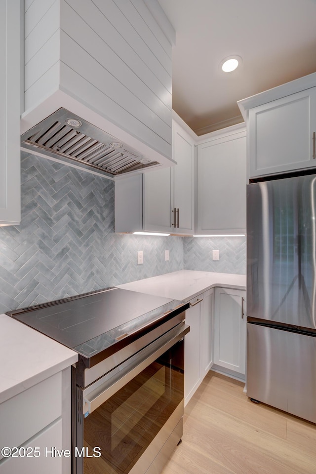 226 Bayfield Dr, Wilmington, NC 28411 - kitchen with appliances with stainless steel finishes, wall chimney range hood, tasteful backsplash, and light countertops