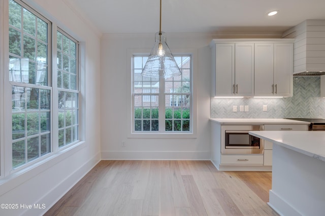 226 Bayfield Dr, Wilmington, NC 28411 - kitchen featuring light countertops, light wood-style flooring, white cabinetry, custom range hood, and decorative backsplash