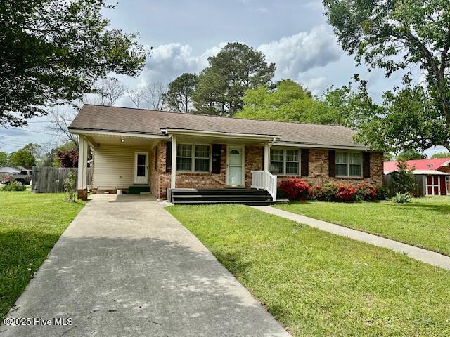 ranch-style house with an attached carport, driveway, fence, and a front lawn