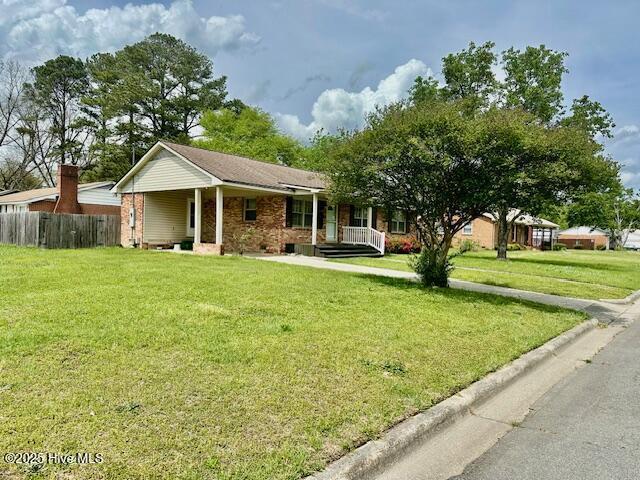single story home with a front yard, fence, brick siding, and covered porch