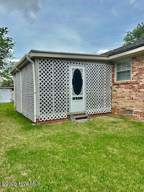 exterior space with crawl space, brick siding, and a lawn