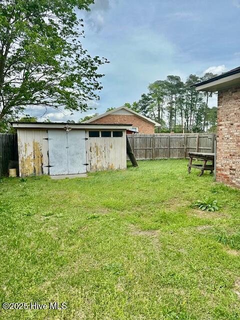 view of yard featuring an outbuilding, fence, and a shed