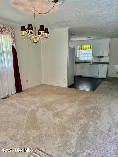 unfurnished living room featuring crown molding, a textured ceiling, a chandelier, carpet flooring, and a sink