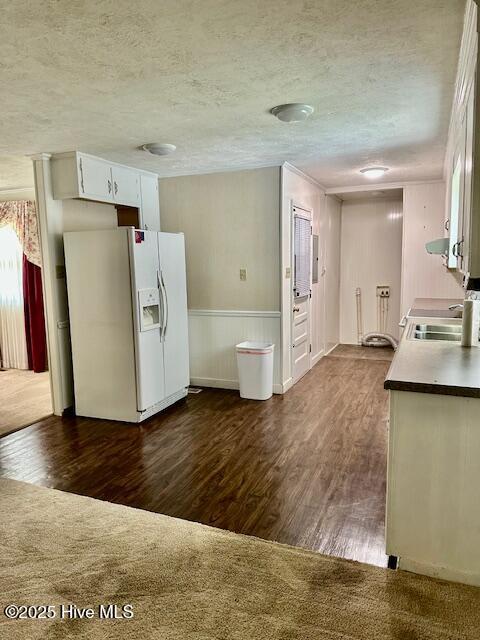 kitchen with dark wood-type flooring, a textured ceiling, a sink, and white fridge with ice dispenser