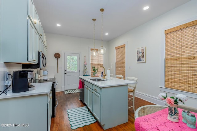 411 Queen St, New Bern, NC 28560 - kitchen featuring appliances with stainless steel finishes, a sink, light countertops, dark wood-type flooring, and an island with sink