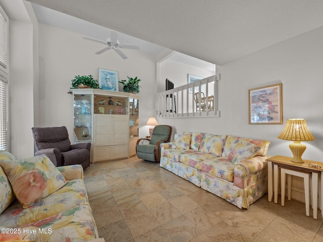 living room featuring ceiling fan, lofted ceiling, and stone finish flooring
