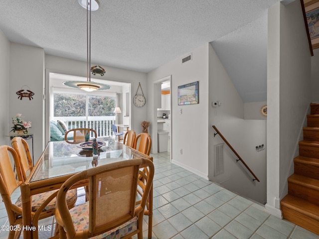 dining area with stairway, light tile patterned flooring, visible vents, baseboards, and a textured ceiling