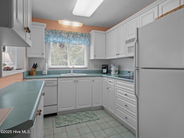 kitchen featuring a sink, light tile patterned floors, white appliances, white cabinetry, and light countertops