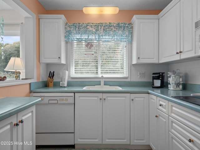kitchen featuring a sink, white dishwasher, white cabinetry, and tasteful backsplash