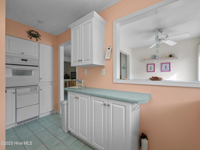 kitchen featuring oven, white cabinetry, ceiling fan, and light tile patterned flooring