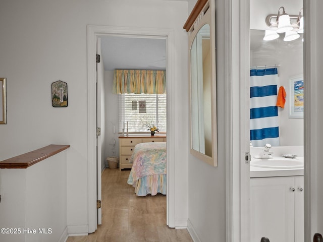 hallway with an inviting chandelier, baseboards, and a sink