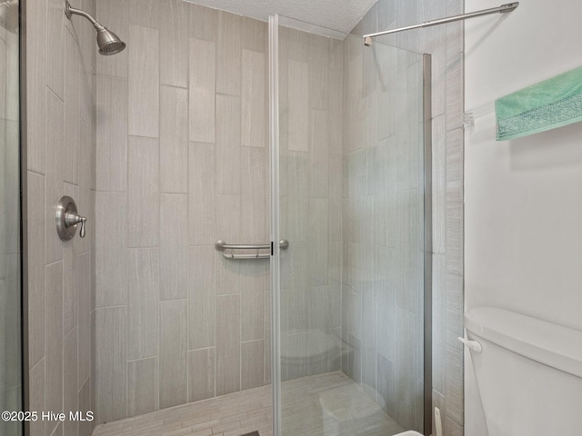 full bathroom featuring a textured ceiling, toilet, and a stall shower
