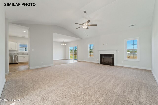 608 Indigo Johnston Dr, Jacksonville, NC 28546 - unfurnished living room featuring a glass covered fireplace, baseboards, visible vents, light colored carpet, and ceiling fan with notable chandelier