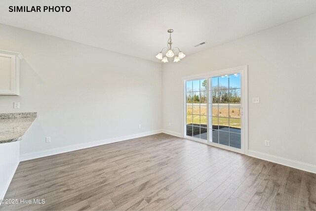 608 Indigo Johnston Dr, Jacksonville, NC 28546 - unfurnished dining area featuring wood finished floors, visible vents, a notable chandelier, and baseboards