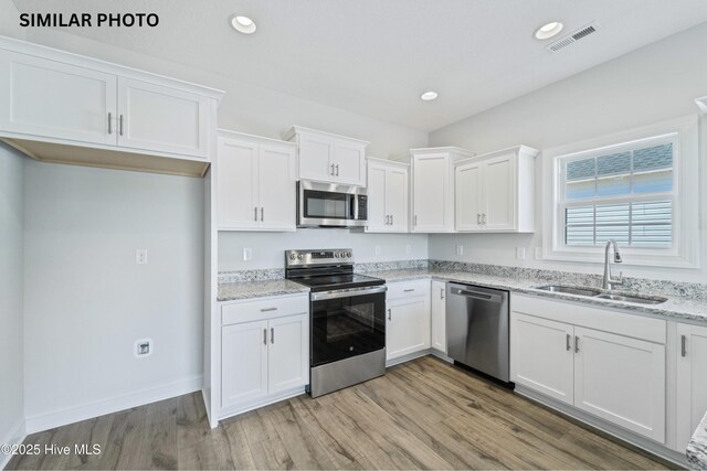 608 Indigo Johnston Dr, Jacksonville, NC 28546 - kitchen featuring light wood-type flooring, appliances with stainless steel finishes, a sink, and white cabinetry