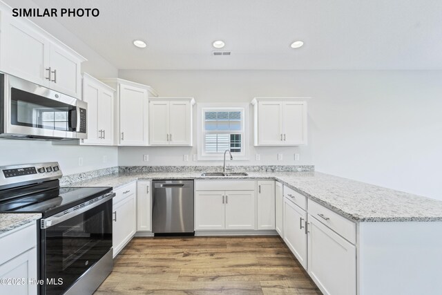 608 Indigo Johnston Dr, Jacksonville, NC 28546 - kitchen with a peninsula, appliances with stainless steel finishes, a sink, and white cabinets
