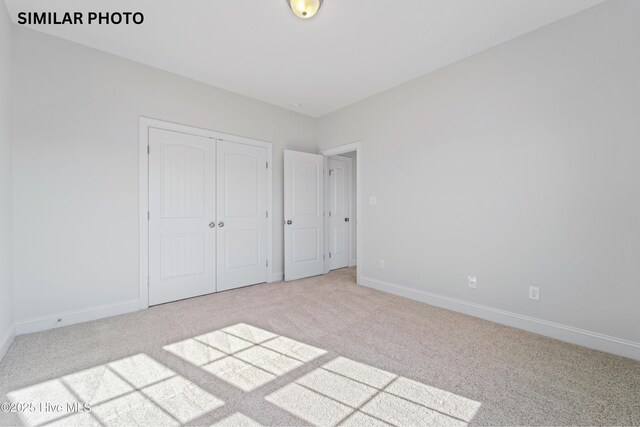 608 Indigo Johnston Dr, Jacksonville, NC 28546 - unfurnished bedroom featuring a closet, baseboards, and carpet