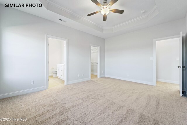 608 Indigo Johnston Dr, Jacksonville, NC 28546 - unfurnished bedroom featuring visible vents, carpet, crown molding, a tray ceiling, and a walk in closet