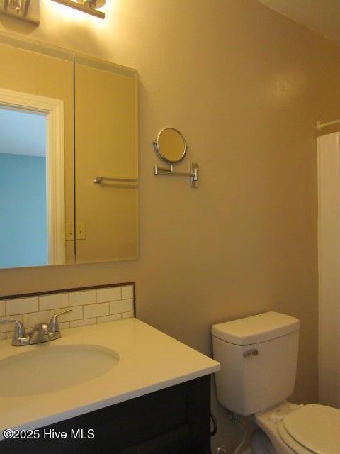 bathroom with vanity, toilet, and decorative backsplash