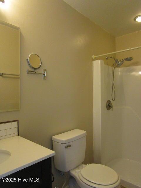 full bath featuring tasteful backsplash, vanity, walk in shower, and toilet
